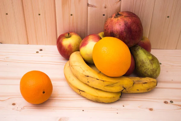 Çeşitli meyve elma, muz, portakal, nar doğal ahşap zemin üzerinde. Sağlıklı gıda