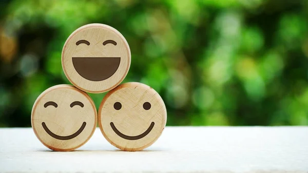 Wooden smile emoji with natural bokeh background. International Day of Happiness and mental health concept.