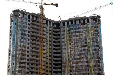 Mavi gökyüzüne karşı binanın yakınında endüstriyel vinç. Şantiye.