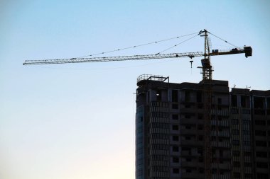 Mavi gökyüzüne karşı binanın yakınında endüstriyel vinç. Şantiye.