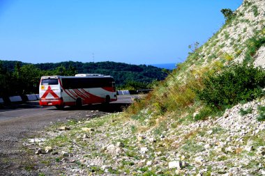 Otobüs dağlar ve deniz arka planda bir şehirde çağırır.