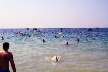 Denizde yüzen ve plajda dinlenen bir grup insan ile açık bir günde Plaj manzara.