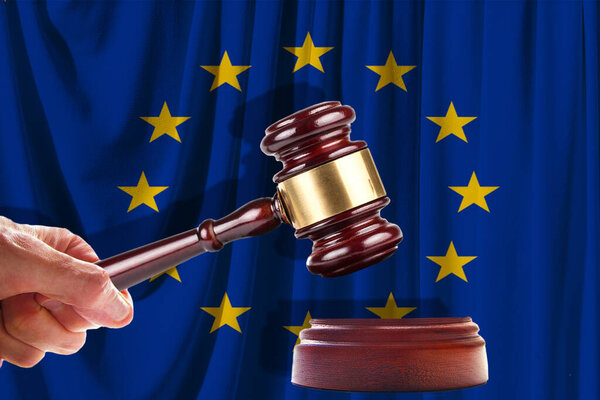 Judge wooden gavel on the background of the flag of European Union. Oil and gas industry. The concept of oil fields and oil companies.