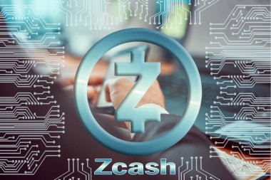 Bilgisayarda çalışan ve akıllı telefonu elinde tutan adamın arka planındaki devre kartı. zcash ZEC kripto para birimi sembolü. Dijital para birimi kavramı, engelleme zinciri, kripto para madenciliği.