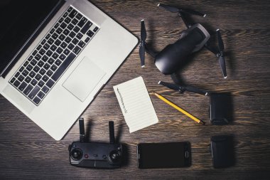 Quadrocopter ahşap arka plan üzerinde dronlar, telefon ve dizüstü bilgisayar aksesuarları hava çekimleri için yerlerin listesi yapmak için sayfa yakınındaki