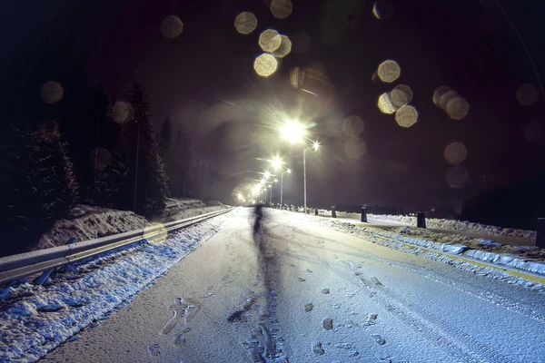 在积雪覆盖的夜间道路上的人的踪迹和剪影 — 图库照片
