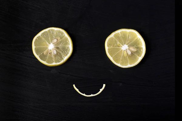 smiling attractive face from lemons on a dark  background, concept of happiness and joy