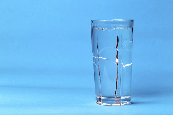 transparent glass with mineral water on a blue background with space for text