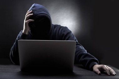 karanlık bir arka plan bir kaputa yüzüne olmadan yorgun hacker