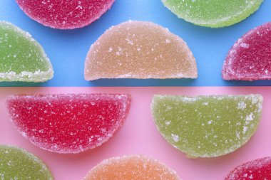 şeker kristalleri pembe-mavi arka plan üzerinde renkli jöle dilimlerle