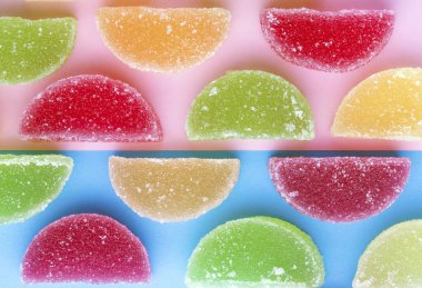 şeker kristalleri pembe-mavi arka plan üzerinde renkli jöle dilimlerle