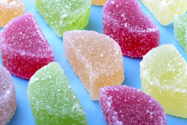 renkli meyve jöle ile mavi bir arka plan üzerinde şeker kristalleri