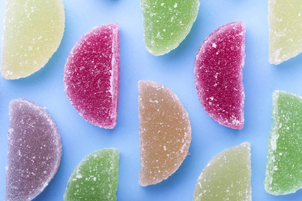 Farbige Fruchtgeleescheiben Mit Zuckerkristallen Auf Blauem Hintergrund — Stockfoto