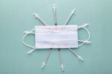 insulin syringes under a protective medical mask, image on azure background clipart