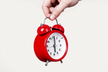 Kırmızı saat hafif bir arka plan üzerinde elinde alarm ile kavram sabah uyanmak.