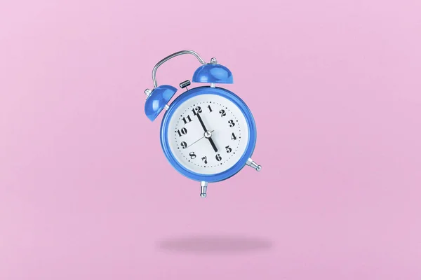 粉红色的背景上的蓝色闹钟 — 图库照片
