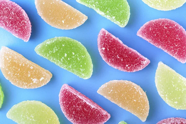 Farbige Fruchtgeleescheiben Mit Zuckerkristallen Auf Blauem Hintergrund — Stockfoto
