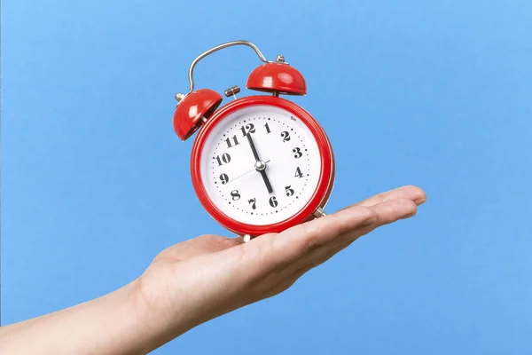 Relógio Vermelho Com Alarme Mão Sobre Fundo Azul — Fotografia de Stock
