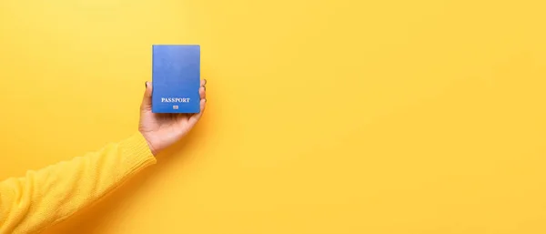 Sarı arka plan üzerinde elinde pasaport — Stok fotoğraf