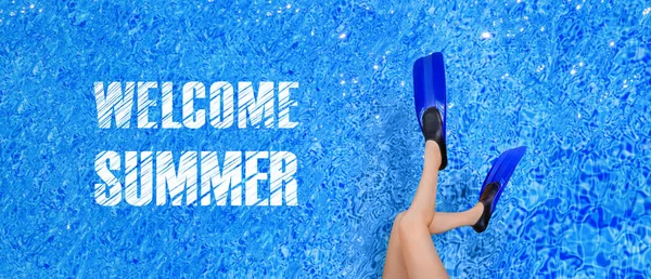 在游泳池的背景上 女性的腿在鳍状肢上 全景图案上刻有欢迎夏天的字样 — 图库照片