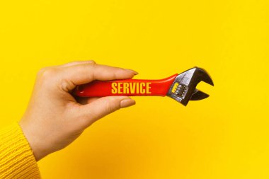 Sarı arkaplandaki kadın elinde kırmızı anahtar üzerinde servis yazıları, araçta usta