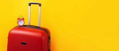 Sarı arka planda alarm saati olan bir seyahat çantası. Yolculuk zamanı. Yolculuk konsepti. Kırmızı valizli geri alarm saati, panoramik model