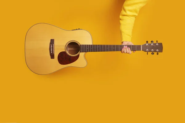 guitar in hand over yellow background, mock-up image