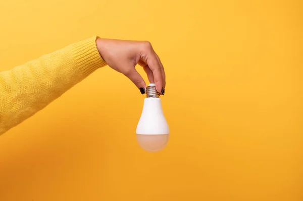 light bulb in hand over yellow background
