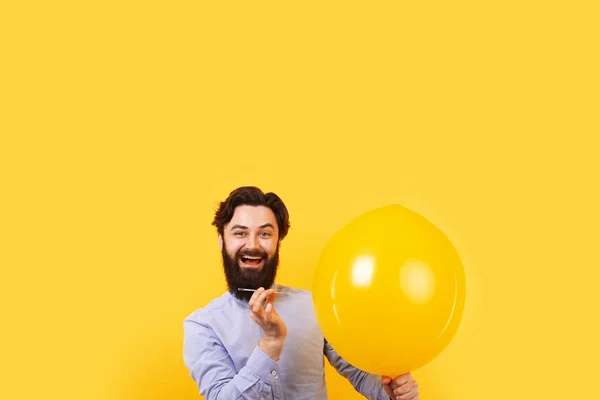 男人拿着针在黄色的气球上 泡沫破裂前片刻 — 图库照片
