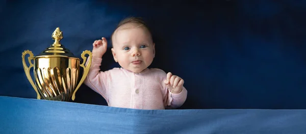 two month old baby with golden cup, victory concept, panoramic mock-up image