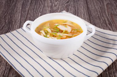 Tavuk suyuna çorba kasesi beyaz keten bir havlu ahşap bir zemin üzerine