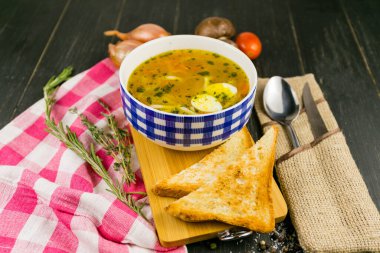 Yumurtalı tavuk çorbası ve ahşap arka planda tost.