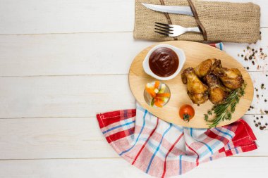 Ahşap arka planda keten havluyla barbekü yapan tavuk bacakları.