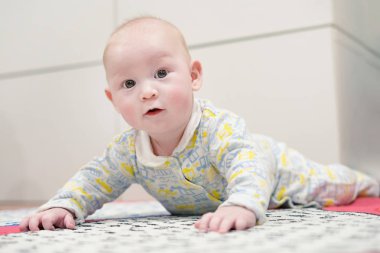 Bebek pijama poke ve tırmanma öğrenir. Oğlan yerde yatıyor