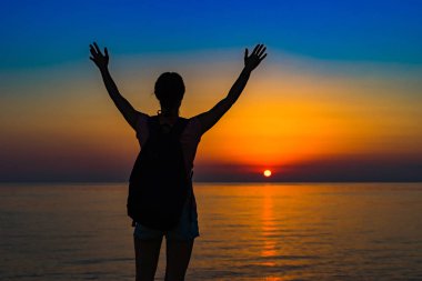 Bir kız elleri deniz kenarında bir kayaya. Deniz kenarında bir sırt çantası ile bir turist. Kızla şafak okyanusta tanışır. Özgürlük ve barış. İçiniz rahat olsun. Deniz meltemi, batan güneşin.