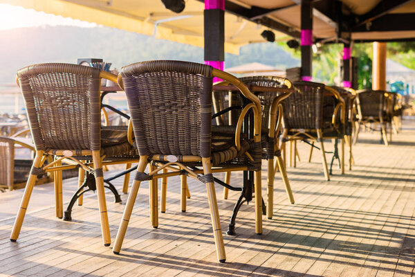 Veranda with chairs. Cafe on the beach. Wicker furniture. Empty restaurant. Light in a cafe.