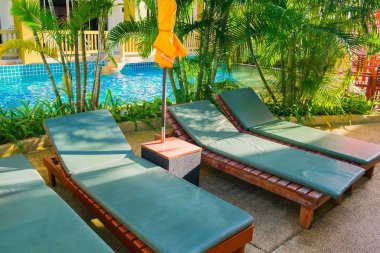 Havuz kenarında boş şezlonglarla otel alanı.