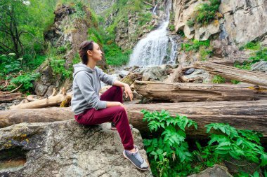 Kız şelale kayaların üzerinde oturur. Tourist adlı dağ şelale taş