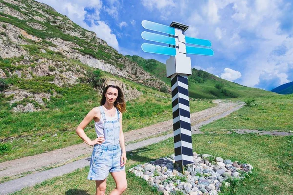 A girl is standing at the direction indicator post.