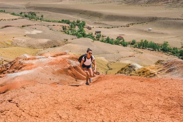 Tourist with a backpack climbs the mountain. Red Mountain Mars in Altai. Woman on the hill