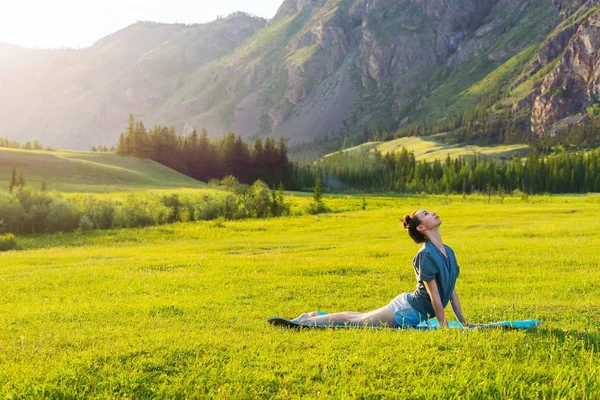 Yoga in the mountains at sunset. Girl doing fitness on the lawn. Evening sunset Relaxation and sport