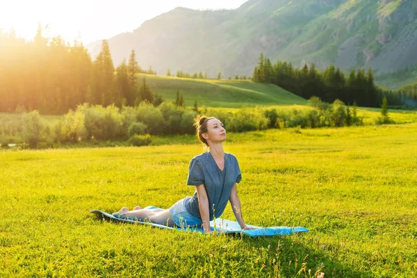 Yoga in the mountains at sunset. Girl doing fitness on the lawn. Evening sunset Relaxation and sport