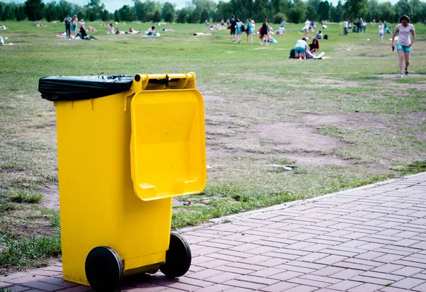 Yellow trash can on the background of nature. Ecology.