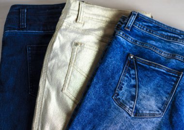 Masanın üzerinde çok renkli kotlar var. Denim. Günlük kıyafet..