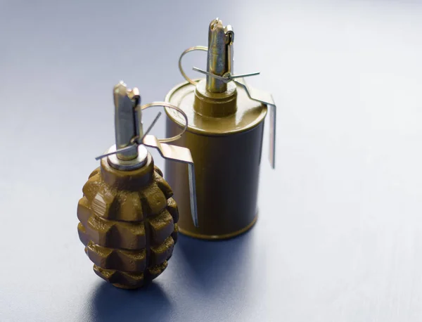 Hand grenades on a gray background. Explosive ammunition is designed to destroy enemy personnel and equipment using manual throwing. Two khaki training smoke grenades.