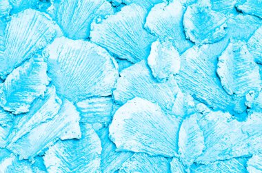 Arka plan açık mavi. Duvarda özel aletlerle yapılmış betondan yapılmış soyut bir çizim. Doku. Taç yaprakları şeklinde dekoratif yüzey çimentodan yapılmıştır. Açık mavi desen.