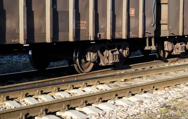part of moving freight train. Wheels of freight car on rails in motion.