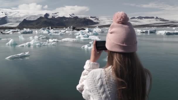 Природа Исландии на пляже Йокульсарлон Айсберг. Женщина-туристка фотографирует с мобильного телефона — стоковое видео