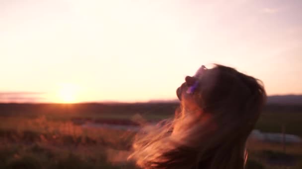 Närbild på ung kvinna promenader med solen i hennes långa hår och vända vid solnedgången — Stockvideo