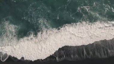 İzlanda'daki siyah volkanik plaj kıyısında geliyor köpük ile vahşi dalgasının havadan görünümü.